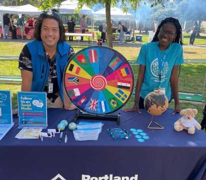 Two female students by a game wheel